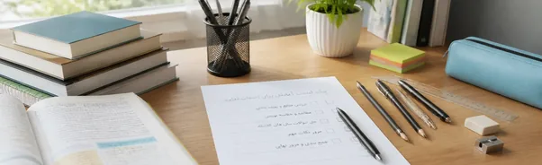 میز مطالعه‌ای مرتب با برگه چک‌لیست فارسی آماده‌سازی برای امتحان نهایی، خودکار، مداد، پاک‌کن، تراش و خط‌کش، در کنار کتاب‌های درسی و یک کتاب باز